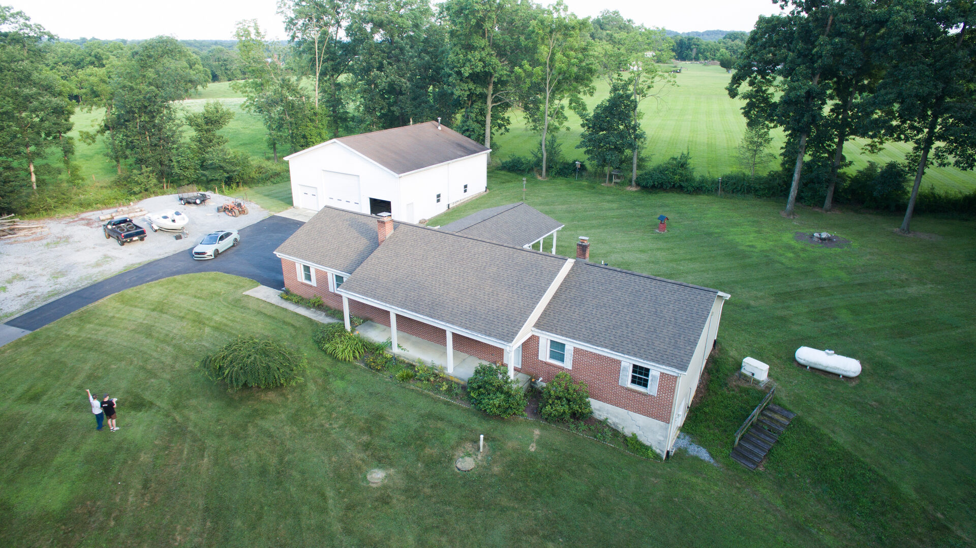 Aerial view of a brick home with detached garage and open countryside