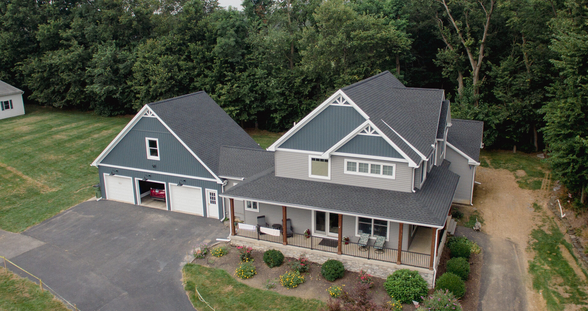 Aerial view of a home with three-car garage and wraparound porch