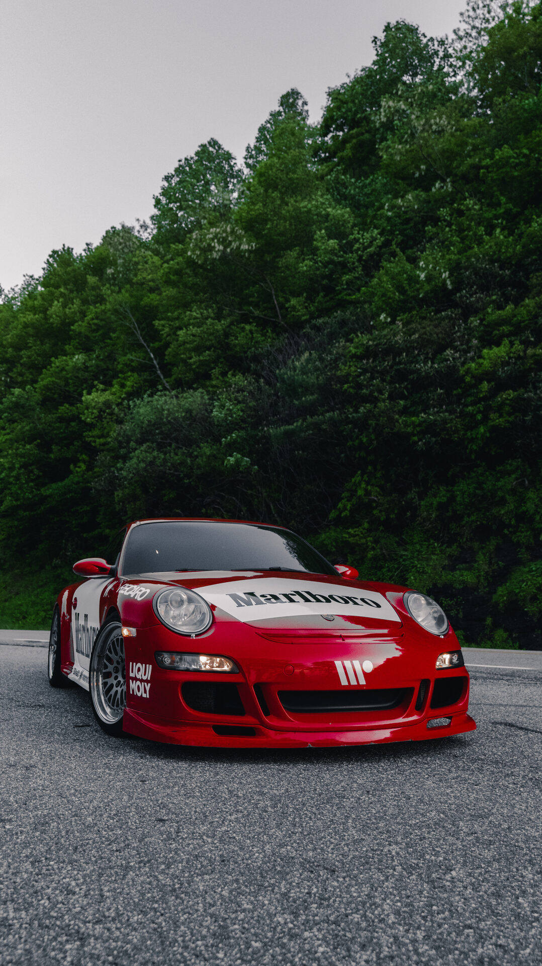 Red and white liveried Porsche 911 parked on a mountain road