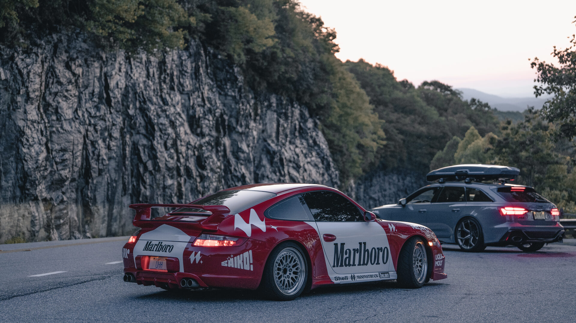 Livery Porsche on a mountain overlook with cliffside backdrop