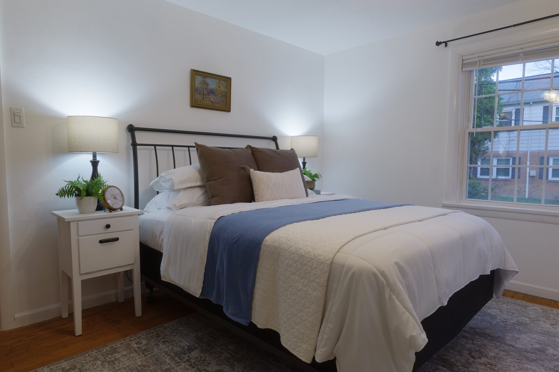 Staged bedroom with iron bed frame and matching nightstand lamps