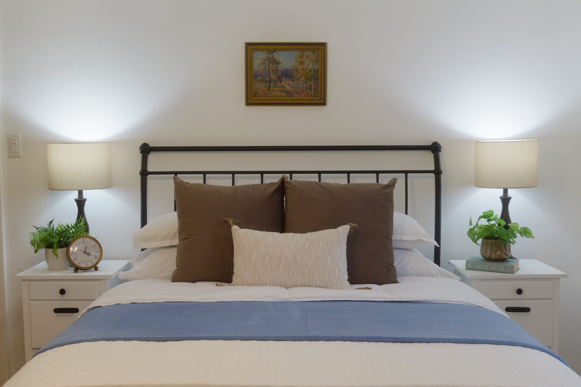 Bedroom headboard detail with framed landscape painting