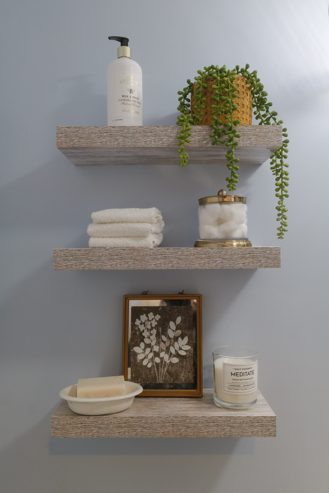 Floating shelves styled with plants, candles, and framed art