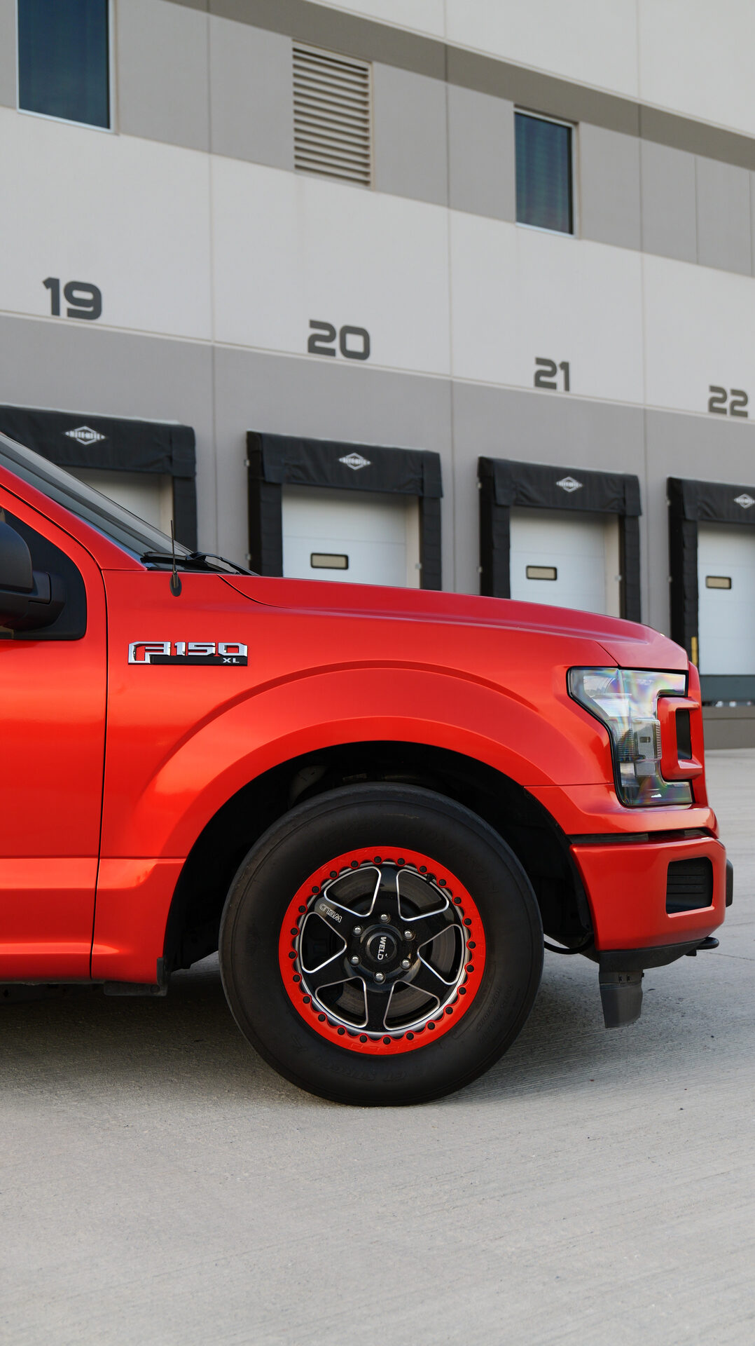 Side profile of red truck wheel with numbered loading docks behind