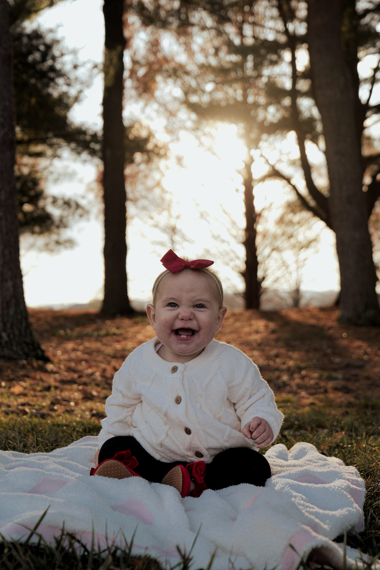 Toddler smiling at the camera with backlit trees